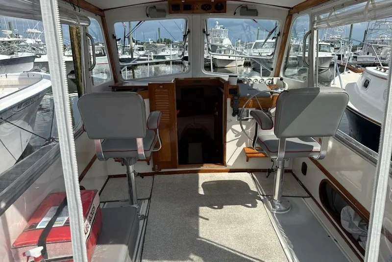 Slide: The Image of Interior of a 2008 Dyer 29 boat with helm, chairs, and marina view. - 4
