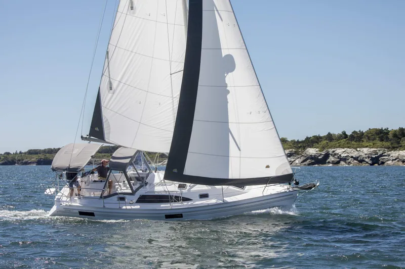 Slide: The Image of Sailing yacht Catalina 316, 2026 model, cruising on open water with rocky shoreline. - 12