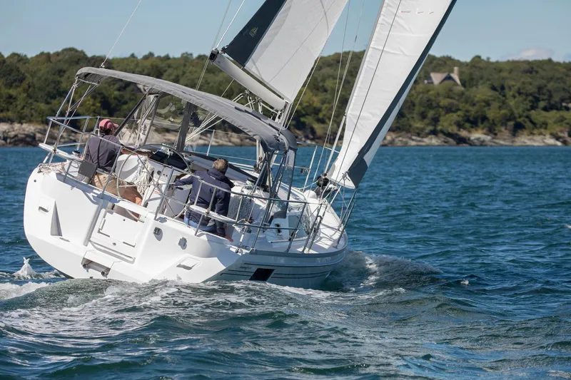 Slide: The Image of Sailing on a 2026 Catalina 316 yacht in clear blue waters, near a forested shoreline. - 8