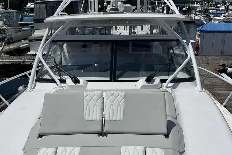 Slide: The Image of 2023 Intrepid 477 Evolution yacht with sleek design and luxurious seating at a marina. - 14