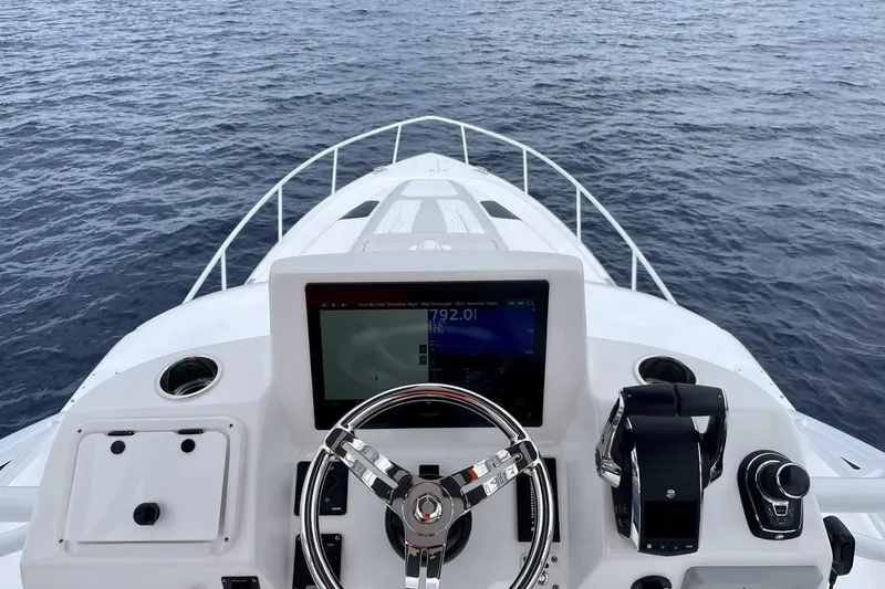 Slide: The Image of 2023 Intrepid 477 Evolution helm with steering wheel and navigation display on open water. - 15