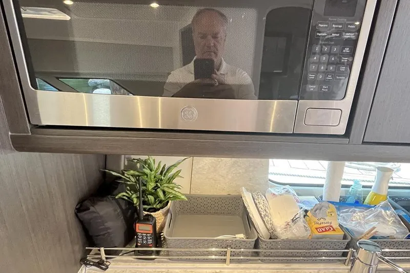 Slide: The Image of Interior of 2023 Intrepid 477 Evolution with microwave, storage baskets, and plant. - 48