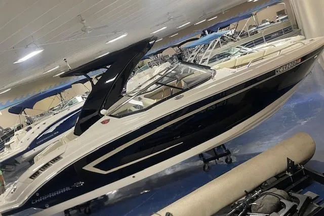 Slide: The Image of 2014 Chaparral 257 SSX boat in showroom, sleek design, white and navy color scheme. - 4