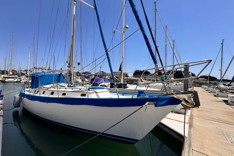 The Image of 1982 Kelly Peterson 46 sailboat docked at marina under clear blue sky. - 0