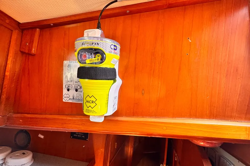 Slide: The Image of Yellow ACR EPIRB mounted on wooden panel inside 1982 Kelly Peterson 46 yacht. - 10