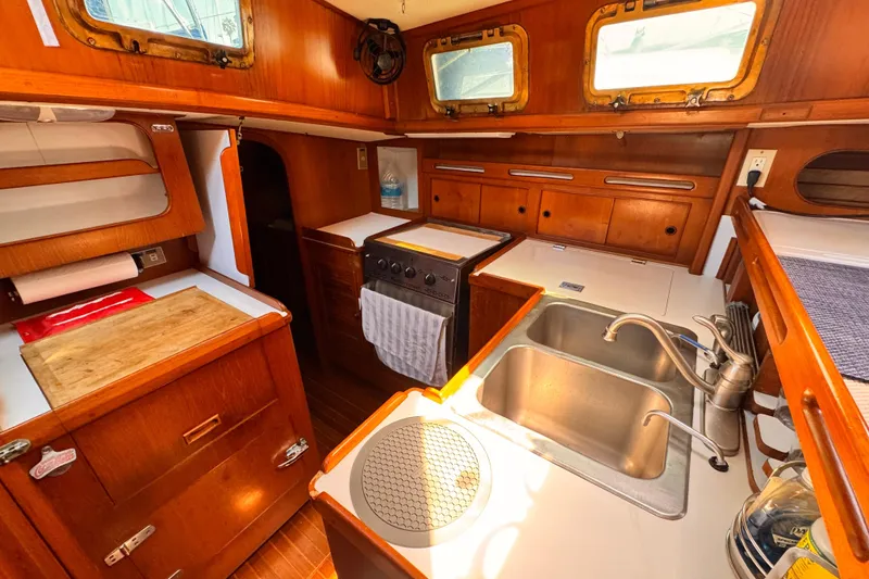 Slide: The Image of 1982 Kelly Peterson 46 yacht interior kitchen with wooden cabinetry and dual sinks. - 12