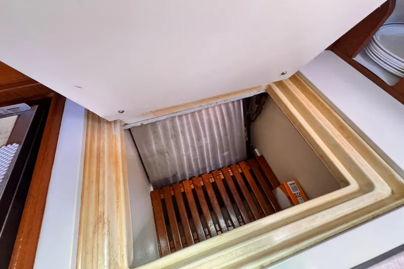 Slide: The Image of Open storage compartment on 1982 Kelly Peterson 46 yacht, featuring wooden slats and a small box. - 16