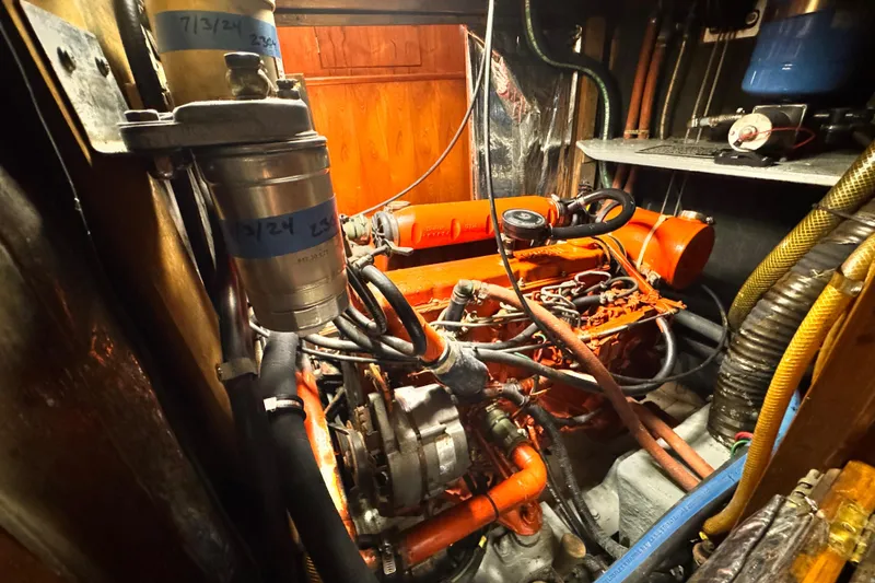 Slide: The Image of Engine room of a 1982 Kelly Peterson 46 sailboat, showcasing mechanical components and wiring. - 28