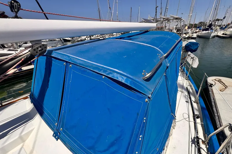 Slide: The Image of 1982 Kelly Peterson 46 sailboat with blue canvas cover docked in marina. - 37