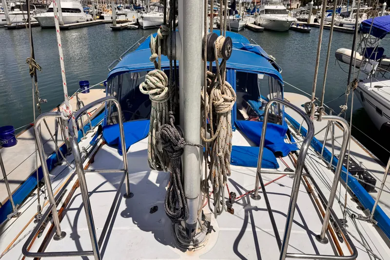 Slide: The Image of Deck view of 1982 Kelly Peterson 46 sailboat in marina, featuring ropes and blue canopy. - 40