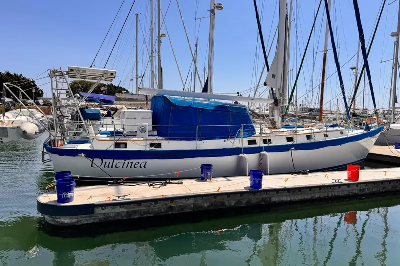 Slide: The Image of 1982 Kelly Peterson 46 sailboat "Dulcinea" docked in a marina, surrounded by other boats. - 48