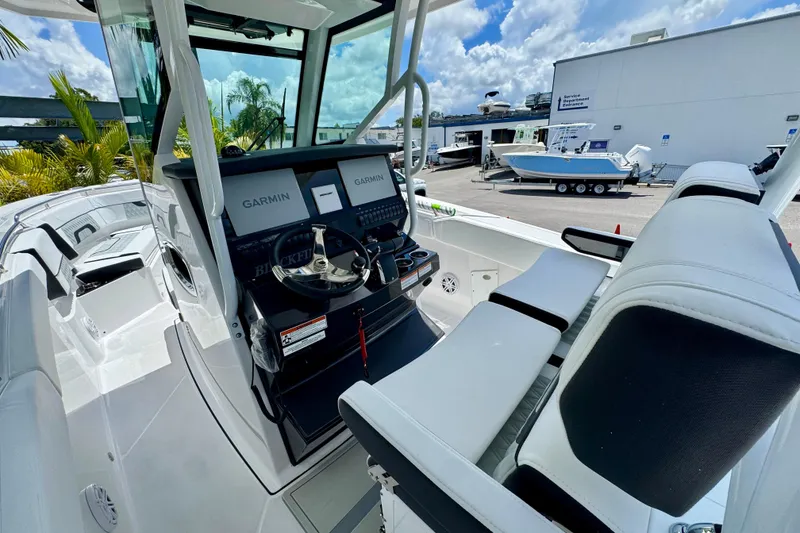 Slide: The Image of 2026 Blackfin 272 CC boat cockpit with Garmin navigation, white seating, and sunny marina backdrop. - 14
