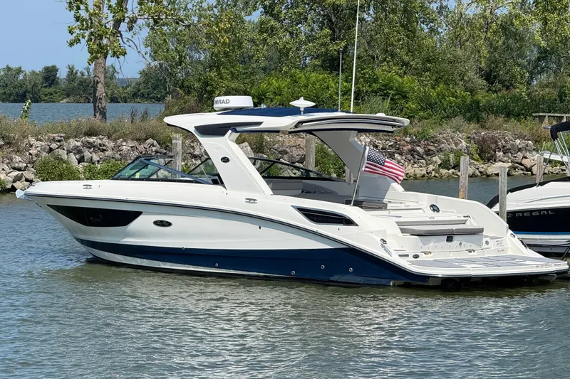 Slide: The Image of 2020 Sea Ray SLX 350 boat docked on a calm lake with trees in the background. - 1