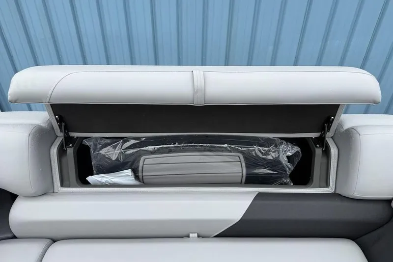 Slide: The Image of 2026 Sun Tracker Party Barge 22 DLX storage compartment with open seat cushion. - 13