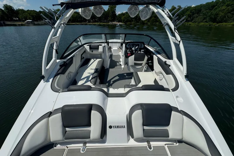 Slide: The Image of 2020 Yamaha AR210 boat interior with seating and steering, on a calm lake. - 5