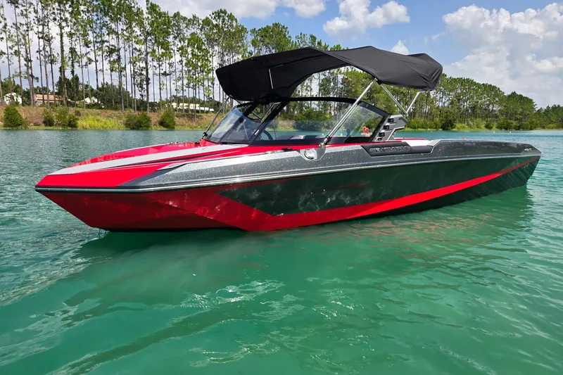 The Image of 2025 Nautique Ski Nautique boat on clear water, featuring sleek red and black design. - 0