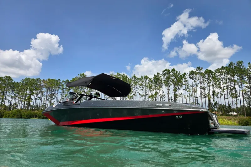 Slide: The Image of 2025 Nautique Ski Nautique boat on clear water with trees and blue sky background. - 13