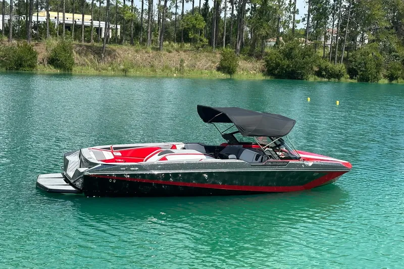 Slide: The Image of 2025 Nautique Ski Nautique boat on a serene lake with lush greenery. - 14