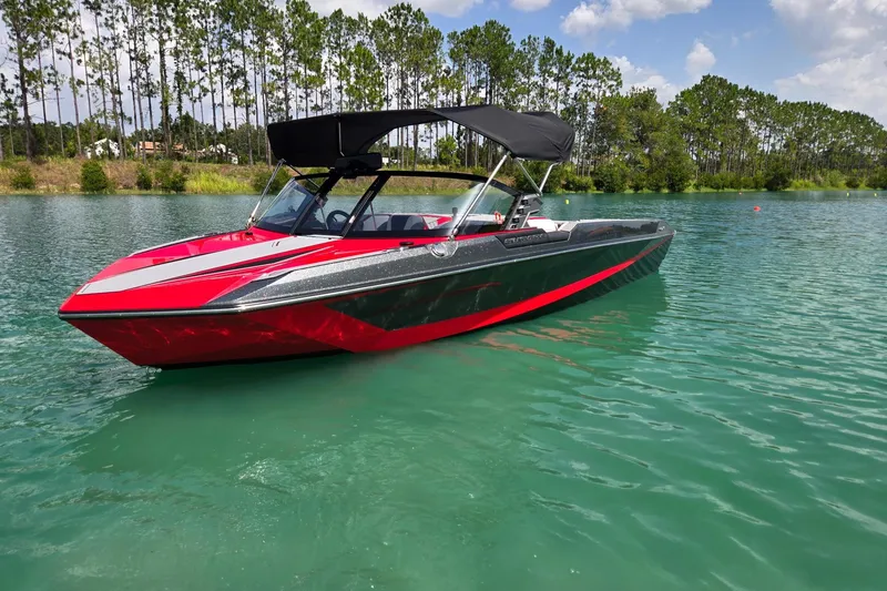 Slide: The Image of 2025 Nautique Ski Nautique boat on a serene lake with lush green surroundings. - 2