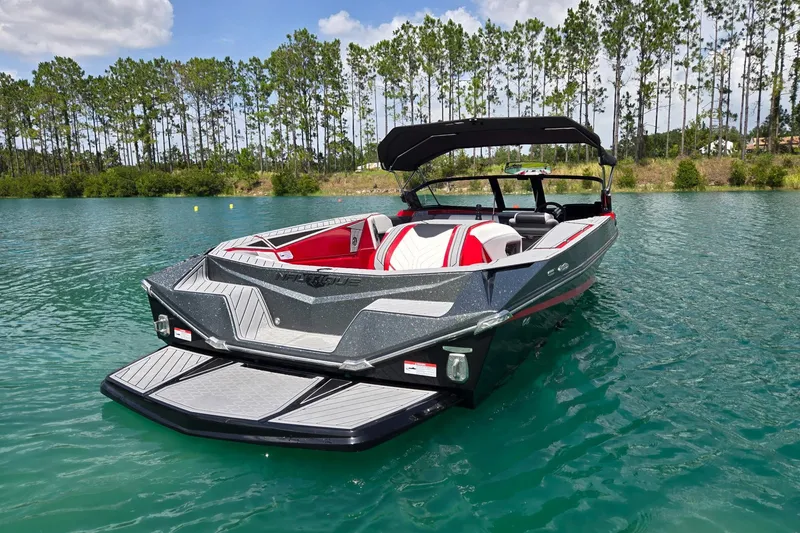 Slide: The Image of 2025 Nautique Ski Nautique boat on a serene lake with lush trees in the background. - 5