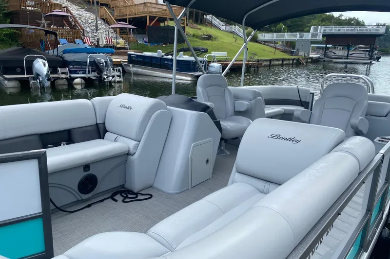 Slide: The Image of 2023 Bentley Pontoons 220 Navigator interior with luxurious seating at a lakeside dock. - 4