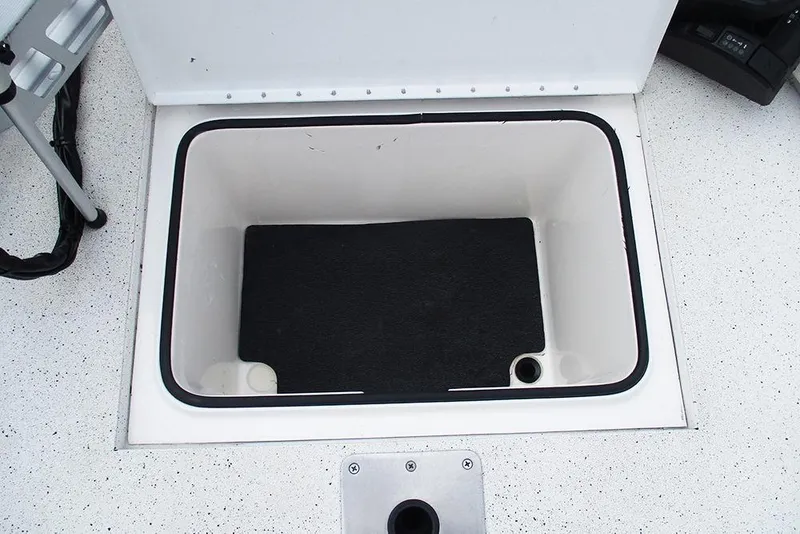 Slide: The Image of Storage compartment of 2023 Vexus AVX2180CC boat, featuring a black mat and drainage hole. - 12
