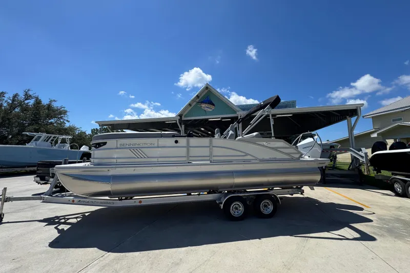 The Image of 2026 Bennington 24 MSB pontoon boat on trailer under clear blue sky. - 1