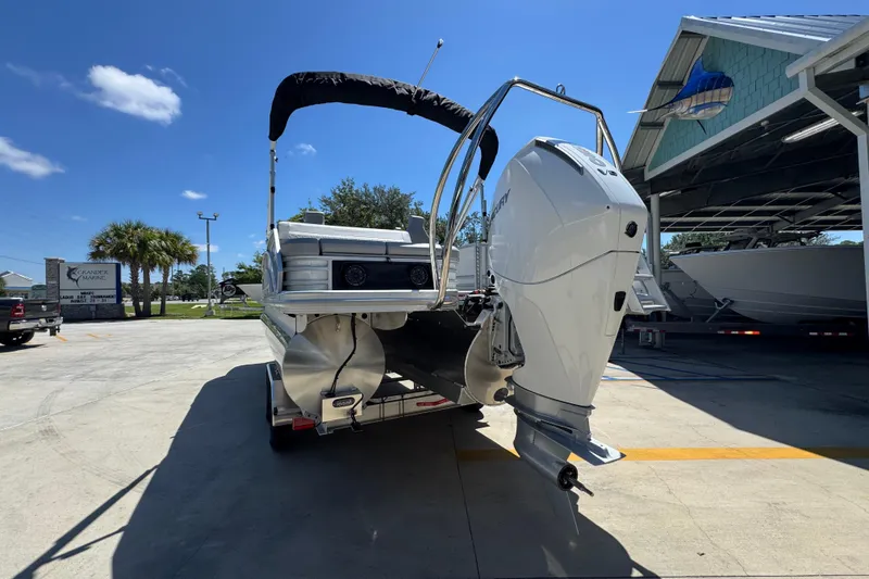 Slide: The Image of 2026 Bennington 24 MSB pontoon boat with powerful outboard motor, parked under clear blue sky. - 15