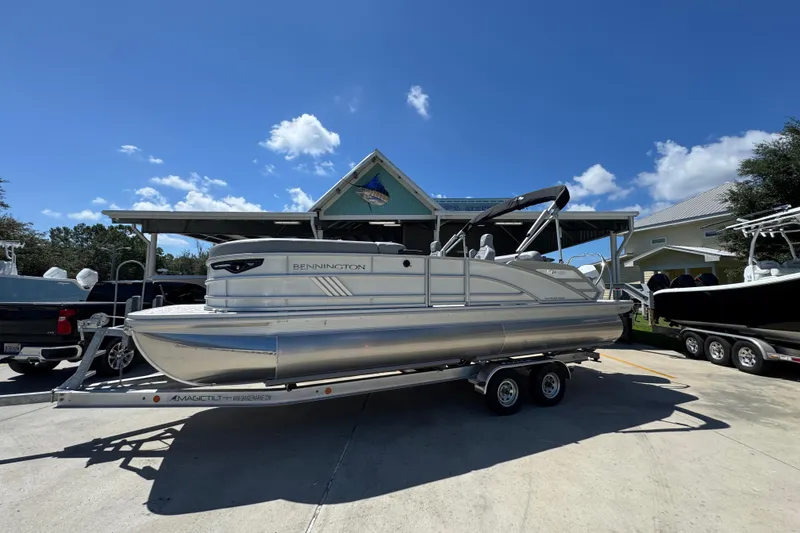 Slide: The Image of 2026 Bennington 24 MSB pontoon boat on trailer under clear blue sky. - 2