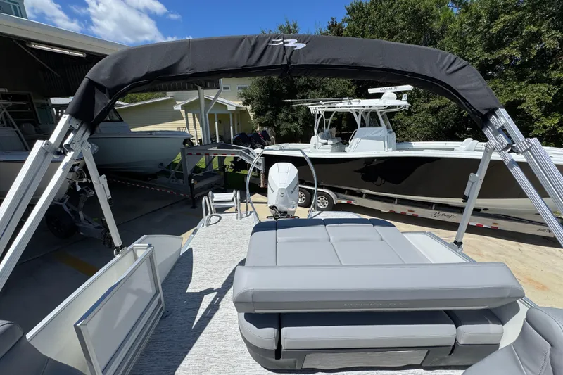 Slide: The Image of 2026 Bennington 24 MSB pontoon boat with canopy, parked near other boats. - 31