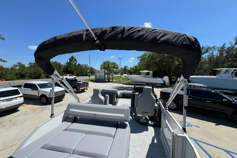 Slide: The Image of 2026 Bennington 24 MSB pontoon boat with canopy, parked in a lot under clear blue sky. - 34