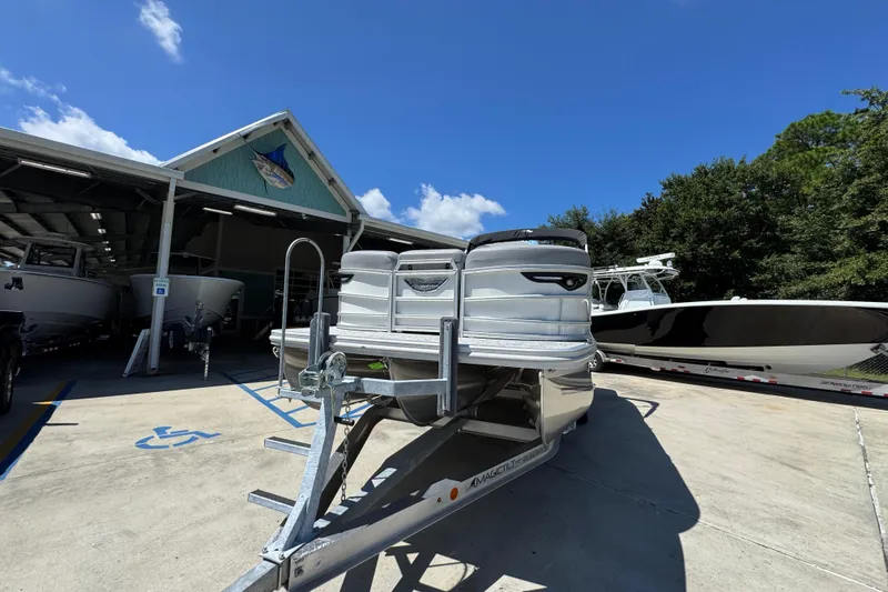 Slide: The Image of 2026 Bennington 24 MSB pontoon boat on trailer outside dealership under clear blue sky. - 5