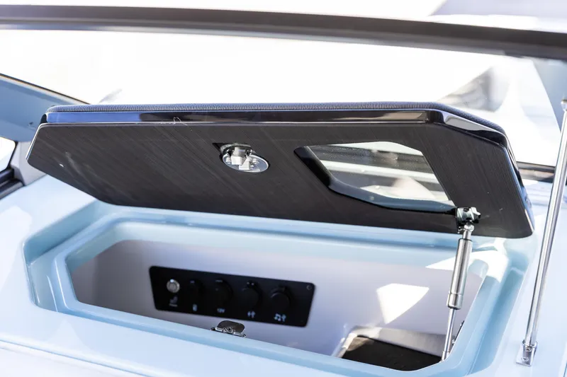 Slide: The Image of 2026 Nautique Super Air Nautique G23 storage compartment with open hatch and control panel. - 22