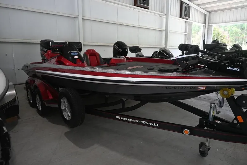 Slide: The Image of 2013 Ranger Z100 Z119 boat in storage, featuring red and black design with trailer. - 2