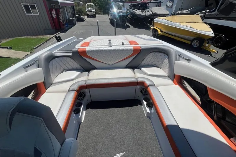 Slide: The Image of 2015 Tigé RZ 2 boat interior with orange and white seating, docked outdoors. - 12