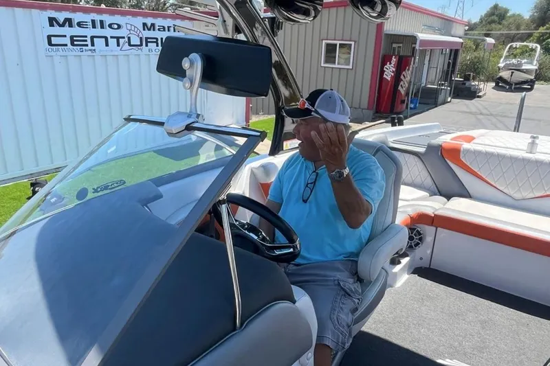 Slide: The Image of Man sitting in a 2015 Tigé RZ 2 boat, gesturing while parked at a marina. - 30