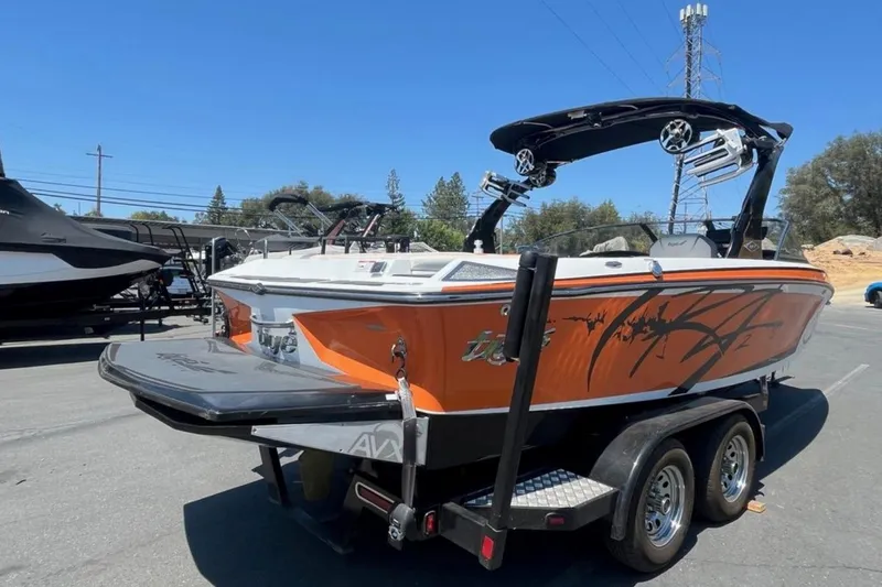 Slide: The Image of 2015 Tigé RZ 2 boat with orange and black design on a trailer in a parking lot. - 33