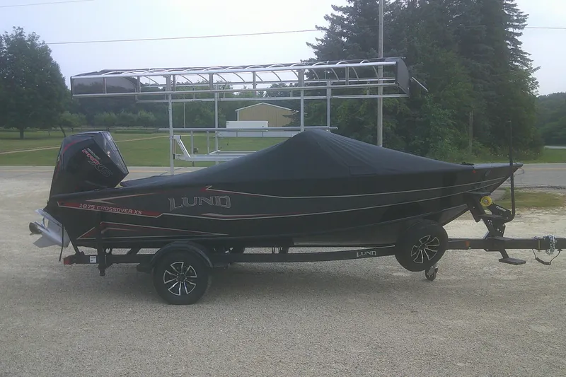 Slide: The Image of 2026 Lund 1875 Crossover XS boat on trailer, covered, parked outdoors. - 16