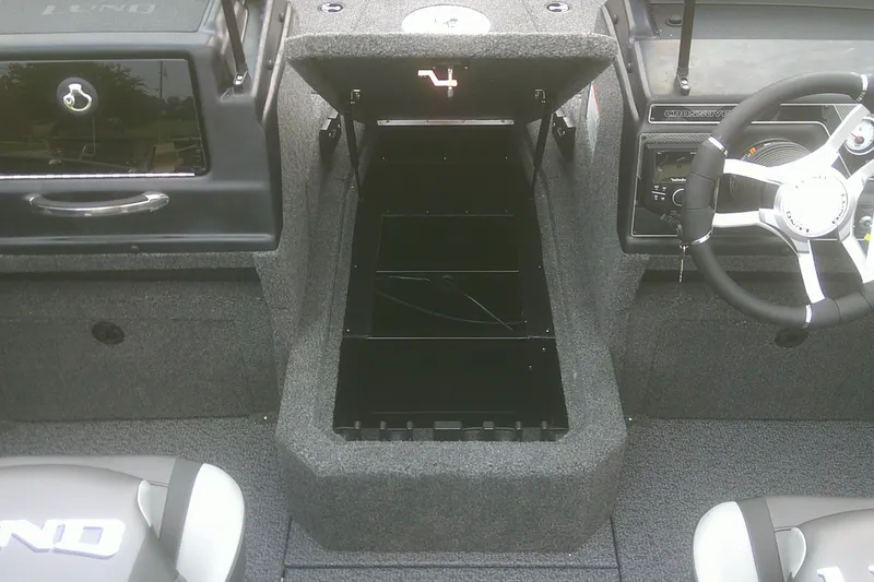 Slide: The Image of 2026 Lund 1875 Crossover XS boat interior with open storage compartment and steering wheel. - 6