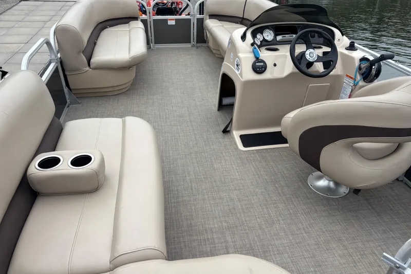 Slide: The Image of 2017 Sun Tracker Party Barge 18 DLX interior with beige seating and steering console. - 2