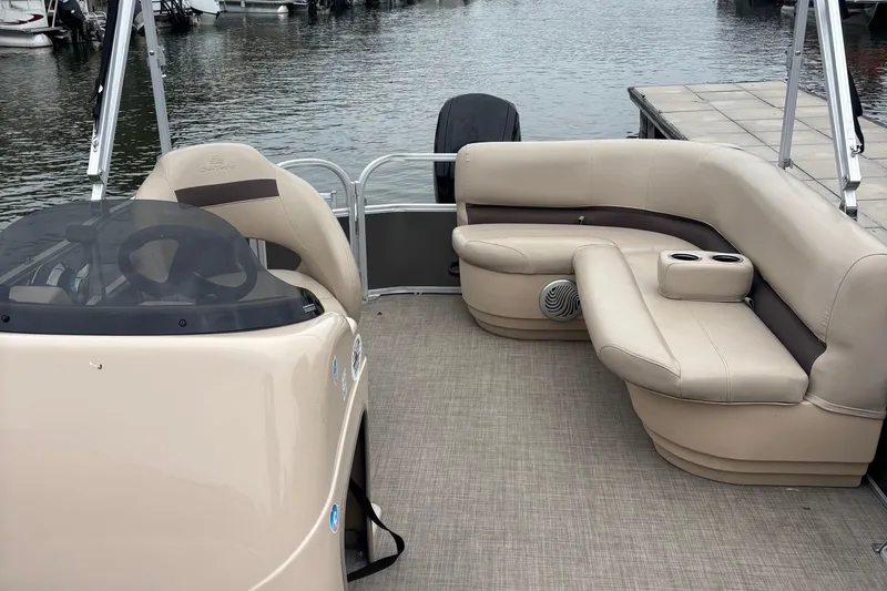 Slide: The Image of 2017 Sun Tracker Party Barge 18 DLX interior with beige seating and steering console. - 4