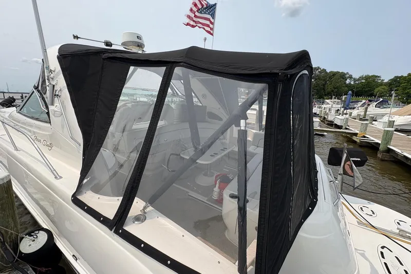 Slide: The Image of 2001 Sea Ray 460 Sundancer yacht docked with American flag, featuring enclosed cockpit. - 14