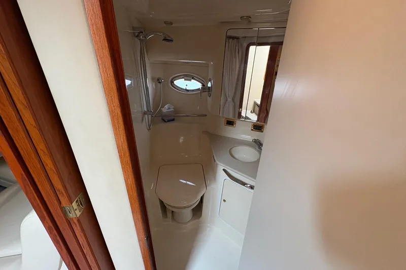 Slide: The Image of 2001 Sea Ray 460 Sundancer bathroom with shower, sink, and wooden door. - 52
