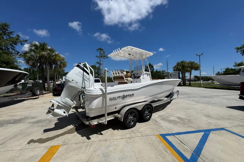 Slide: The Image of 2026 NauticStar 231 Hybrid boat on trailer, parked outdoors under clear blue sky. - 10