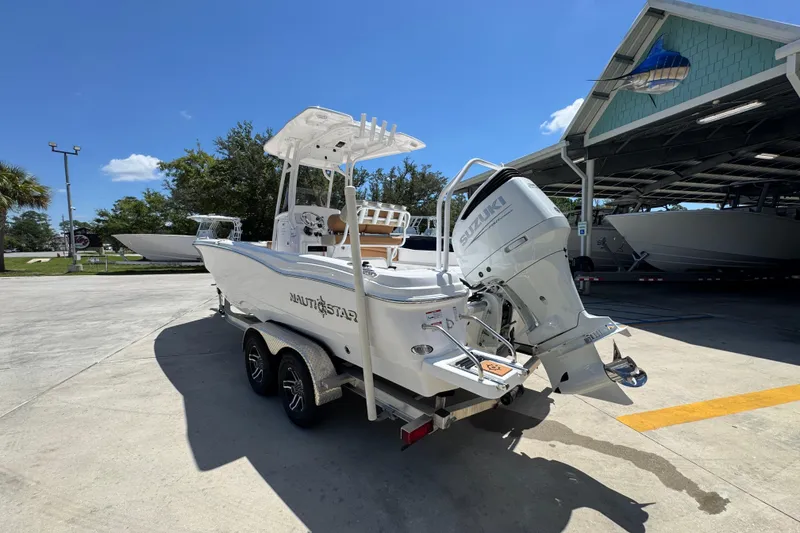 Slide: The Image of 2026 NauticStar 231 Hybrid boat with Suzuki engine on trailer, parked outdoors. - 14