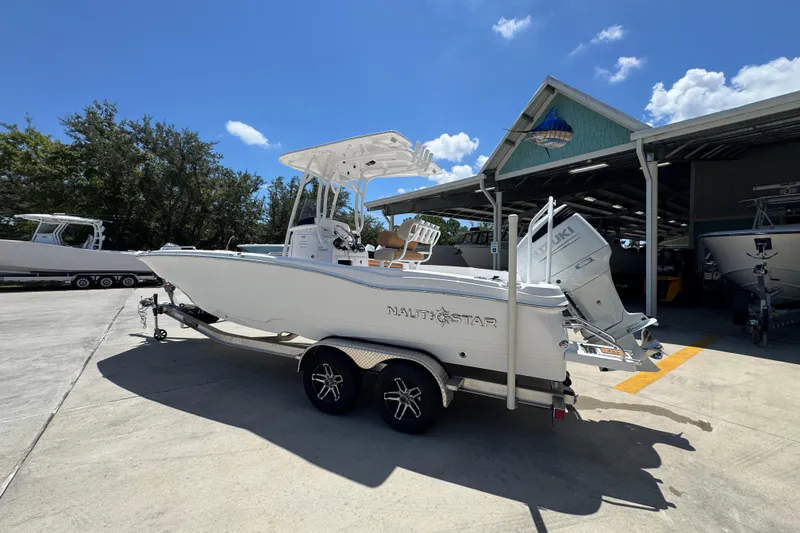 Slide: The Image of 2026 NauticStar 231 Hybrid boat on trailer, parked outdoors under clear blue sky. - 15