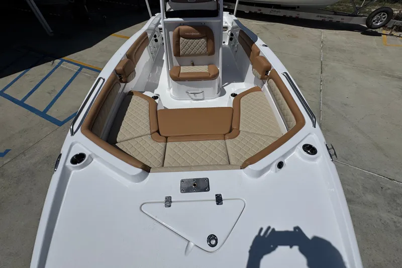 Slide: The Image of 2026 NauticStar 231 Hybrid boat interior with tan and cream seating, docked on concrete. - 19