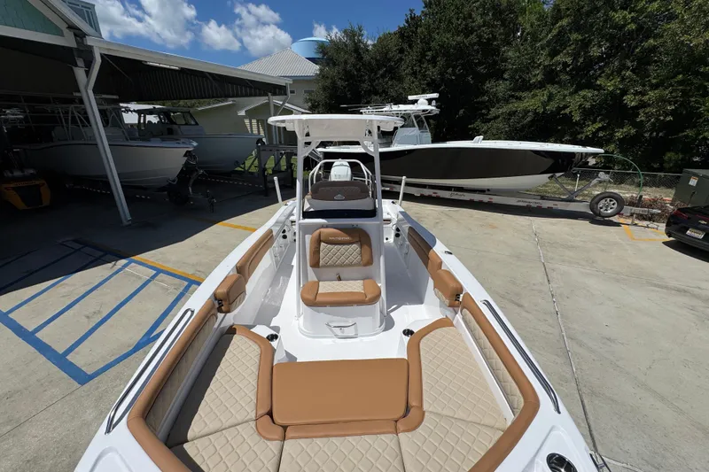 Slide: The Image of 2026 NauticStar 231 Hybrid boat with tan seating, docked outdoors under a clear sky. - 20
