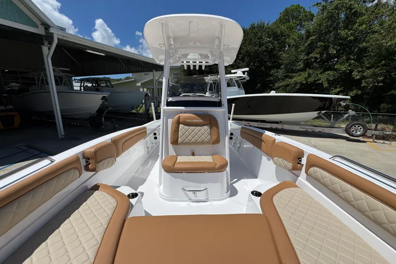 Slide: The Image of 2026 NauticStar 231 Hybrid boat interior with tan and white seating, docked outdoors. - 21