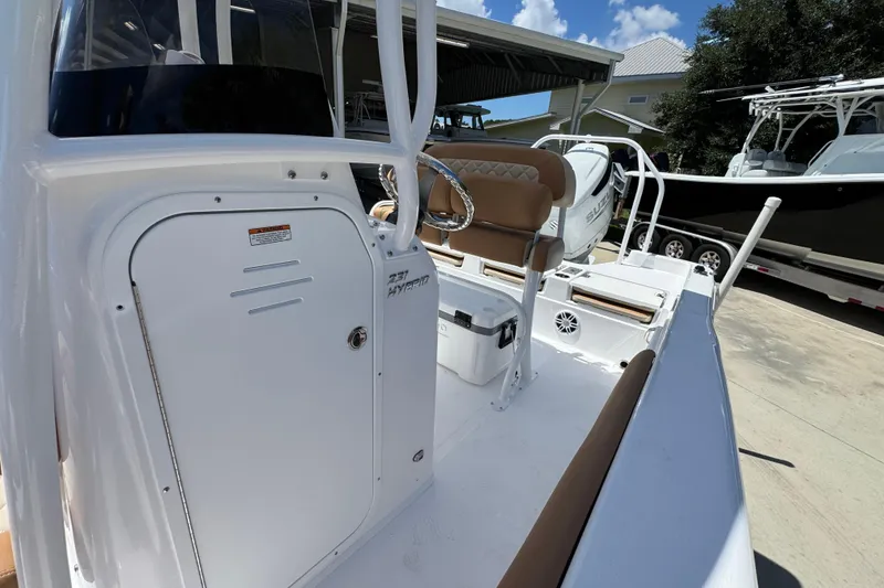 Slide: The Image of 2026 NauticStar 231 Hybrid boat interior with seating and storage, parked outdoors. - 22